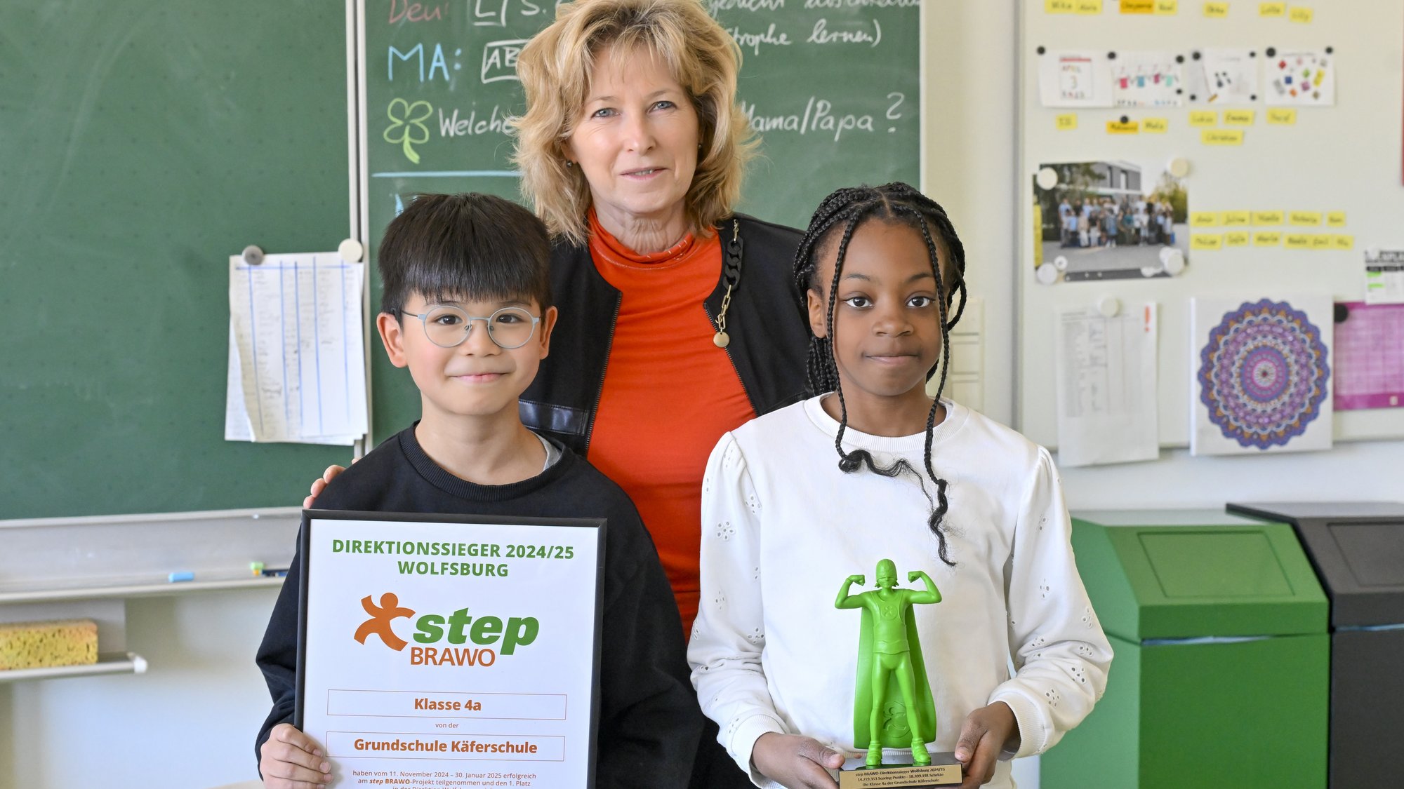 Auf dem Bild sieht man eine Frau mit zwei Kindern. Das linke Kind hält die step BRAWO Urkunde in der Hand und das rechts Kind den grünen step BRAWO-Pokal.
