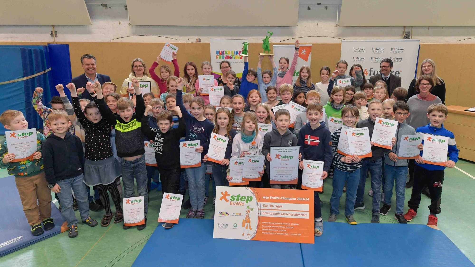 Eine Gruppe mit einigen Erwachsenen steht lachend und jeder mit einer Urkunde der step BraWo in der Hand.
