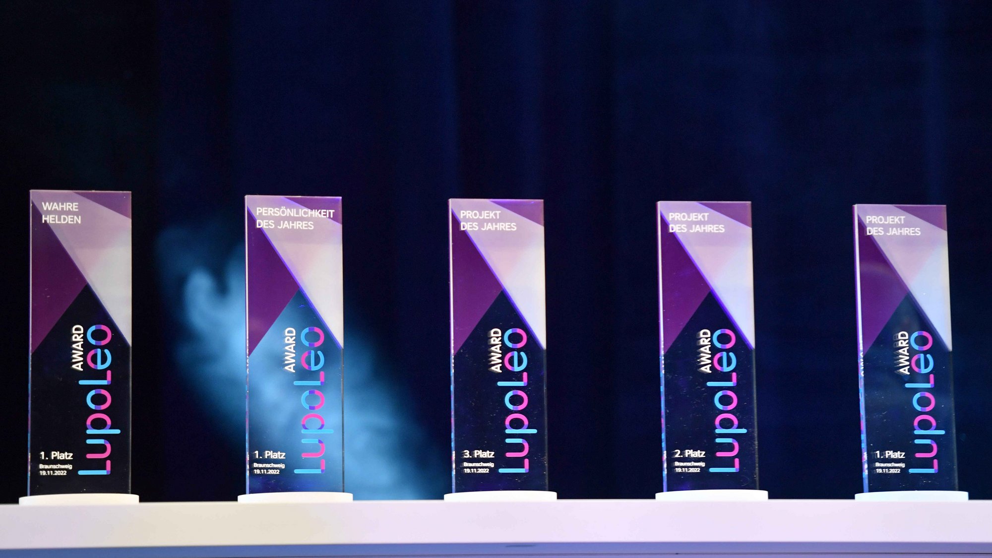 Fünf Lupoleo Awards aus Glas mit den Aufschriften 'Wahre Helden', 'Persönlichkeit des Jahres', 'Projekt des Jahres' und Platzierungen von 1. bis 3. Platz