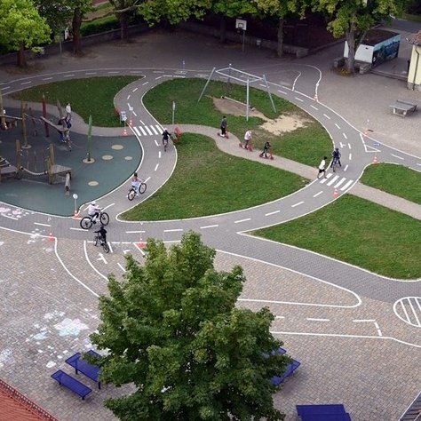 Das Bild zeigt einen Fahrradverkehrsübungsplatz aus der Vogelperspektive. Zwischen den simulierten Fahrradstraßen befindet sich ein Spielgerüst.